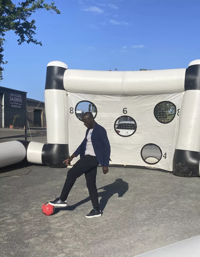 Homme jouant au football devant cible gonflable
